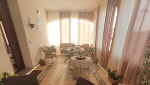 Un comedor con una mesa dispuesta para dos personas, sillas y una mesa de buffet con alimentos.