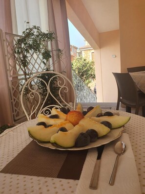 A table with a fruit platter, a metal chair, and a dining table with a chair. - B&B Sos Manneddos (Posada)