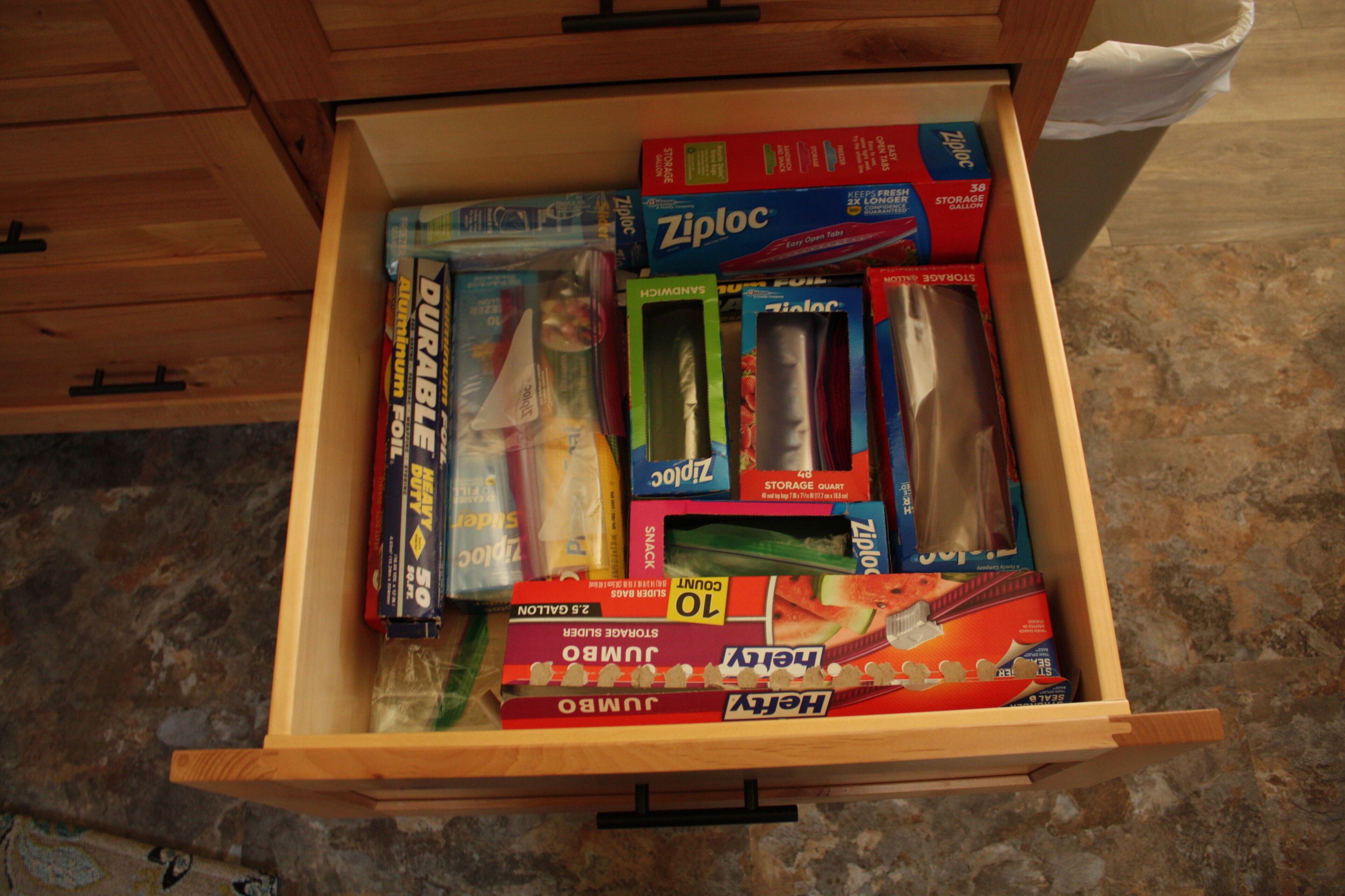 A drawer filled with various items including boxes of Ziploc, Jumbos, and other products.