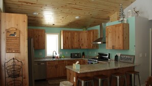 Una cocina con armarios de madera, encimera de granito y refrigerador de acero inoxidable.