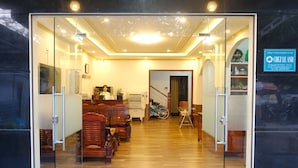 A hotel lobby with a wooden floor, glass doors, and a staircase leading to another level. - Chez Le Anh (Da Nang)