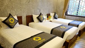 A hotel room with three beds, each with a white bedspread and a black and yellow logo on the headboard. - Chez Le Anh (Da Nang)