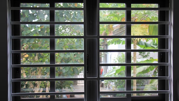 A window with a grid pattern, allowing views of greenery outside. - Chez Le Anh (Da Nang)