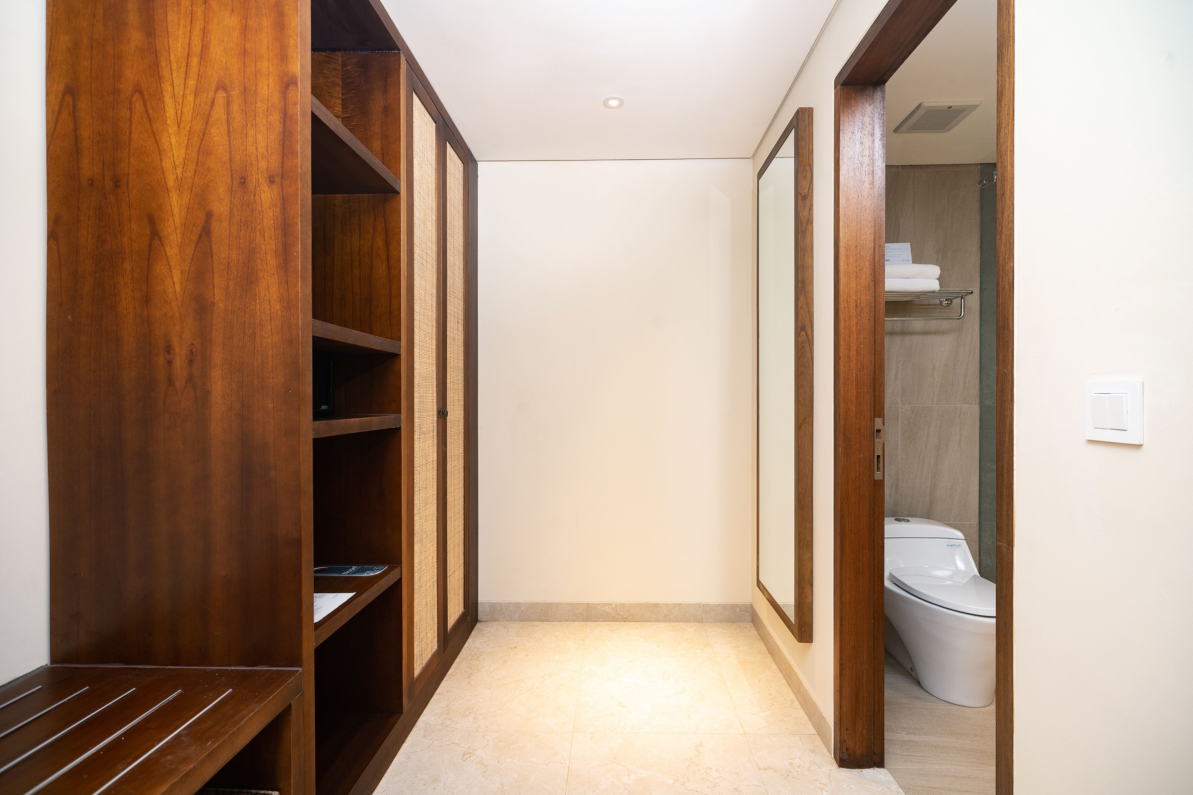 A narrow hallway with wooden shelving units and a white tiled floor.