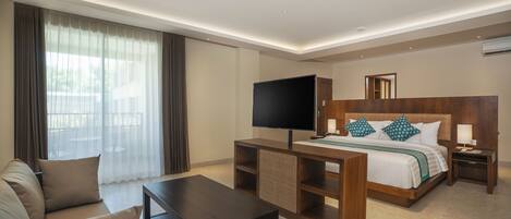 A modern hotel room with a bed, TV, sofa, and a small table.