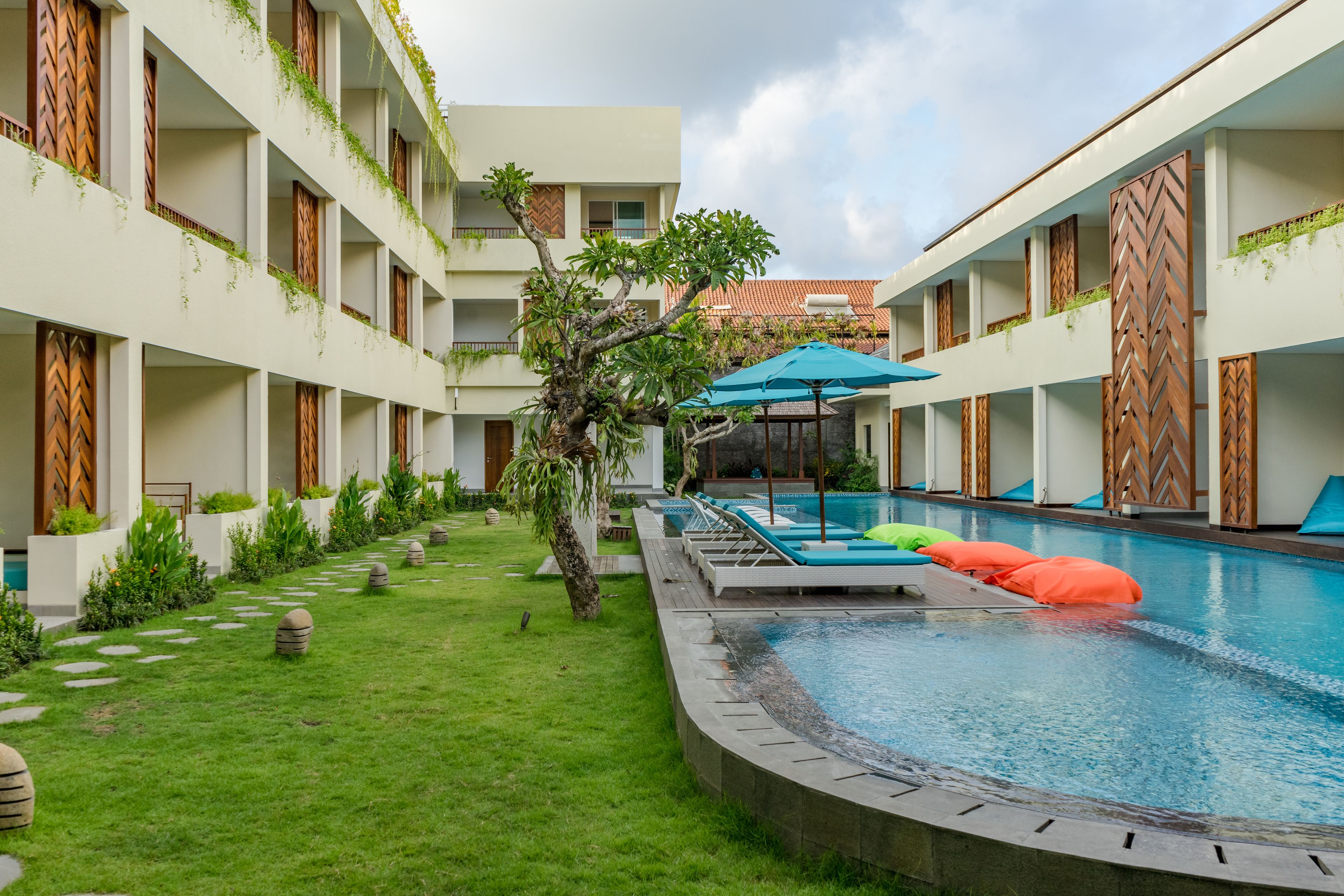 A pool area with a circular pool, lounge chairs, and a small tree.