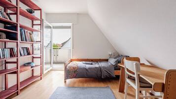Un dormitorio pequeño y acogedor con cama altillo, un escritorio de madera y una estantería.