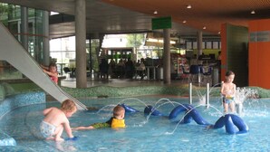 Ein Schwimmbeckenbereich mit Rutsche, Wasserspielplatz und Kinderspielzone.
