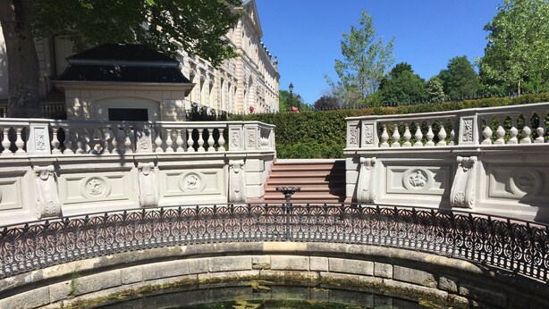 Eine Steinkonstruktion mit aufwändig gestalteten Brüstungen und einer spiegelnden Wasseroberfläche darunter.