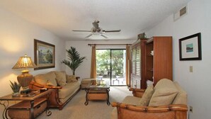 A living room with a ceiling fan, a sofa, a coffee table, and a bookshelf.