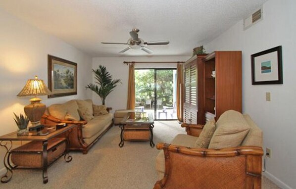 A living room with a ceiling fan, a sofa, a coffee table, and a bookshelf.