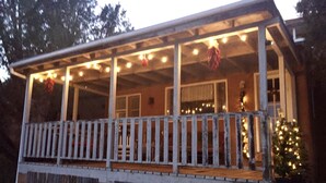 Un portico coperto con ringhiera, luci a stringa e un albero di Natale.
