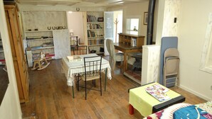 Una stanza accogliente con pavimento in legno, un tavolo da pranzo con sedie, una libreria e una scrivania con una sedia.