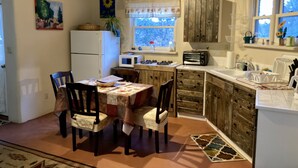 Una cucina con mobili in legno, un frigorifero, un forno a microonde, un tostapane e un'area pranzo con sedie e un tavolo.
