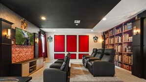 A home theater room with a fireplace, leather recliners, a bookshelf, and a large flat-screen TV. - 5 BD / 5.5 BA/ Solara Resort (9026 PC) (Kissimmee)