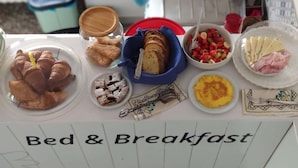A breakfast table with various food items including croissants, bread, a fruit salad, and cheese. - B&B De Angelis (Ginosa)