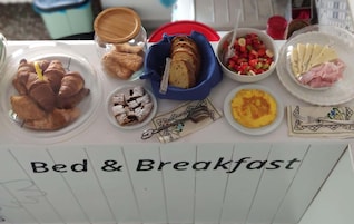 Una mesa de desayuno con diferentes alimentos, como cruasanes, pan, una ensalada de frutas y queso.