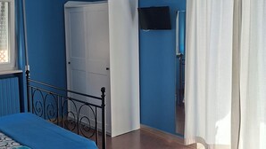A room with a bed, a table, a chair, a wardrobe, and a ceiling light. - B&B De Angelis (Ginosa)