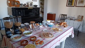 A dining table with various food items and a piano in the background. - B&B De Angelis (Ginosa)