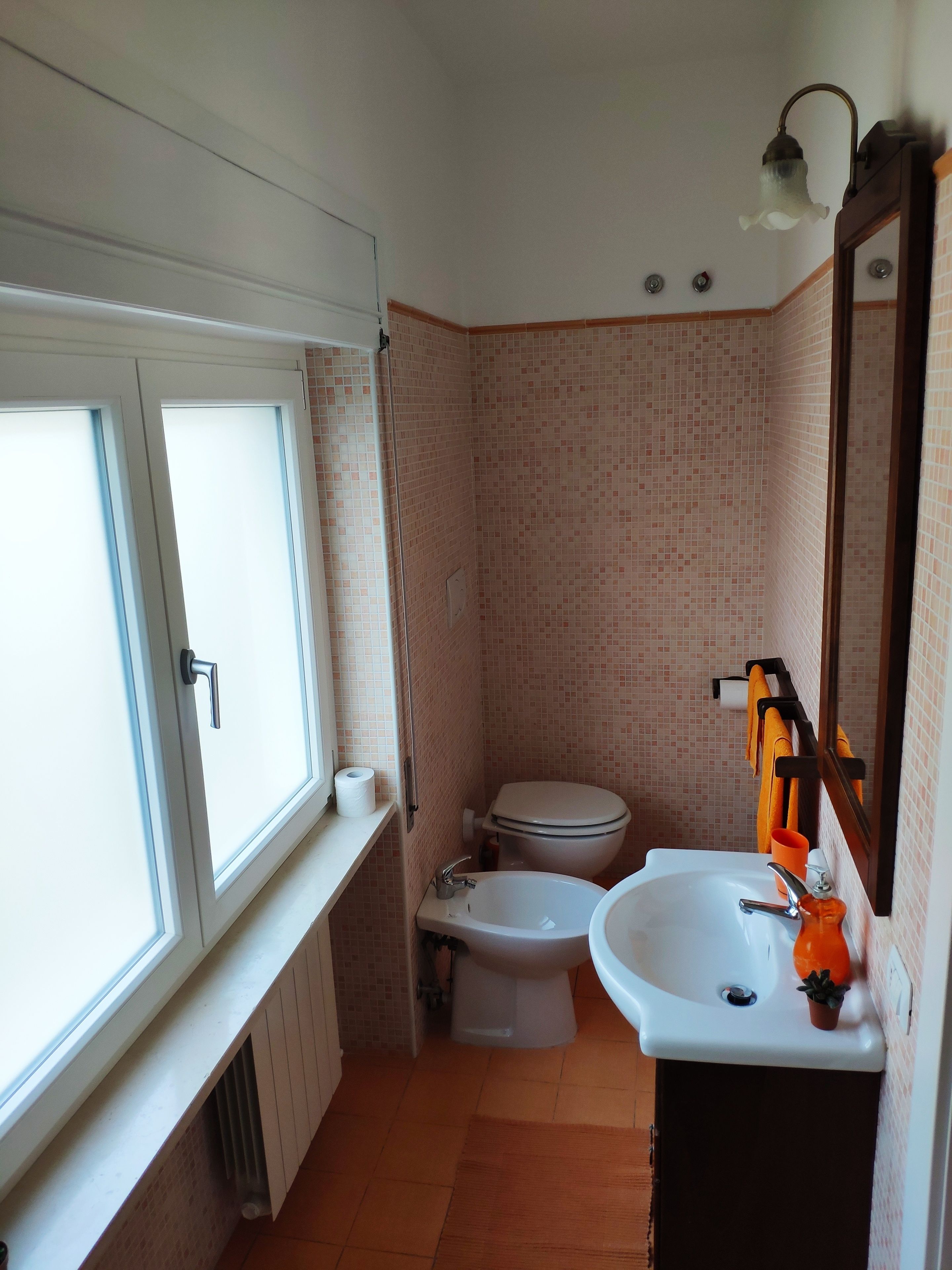 Une salle de bain comprenant des toilettes, un bidet, un lavabo et une fenêtre.