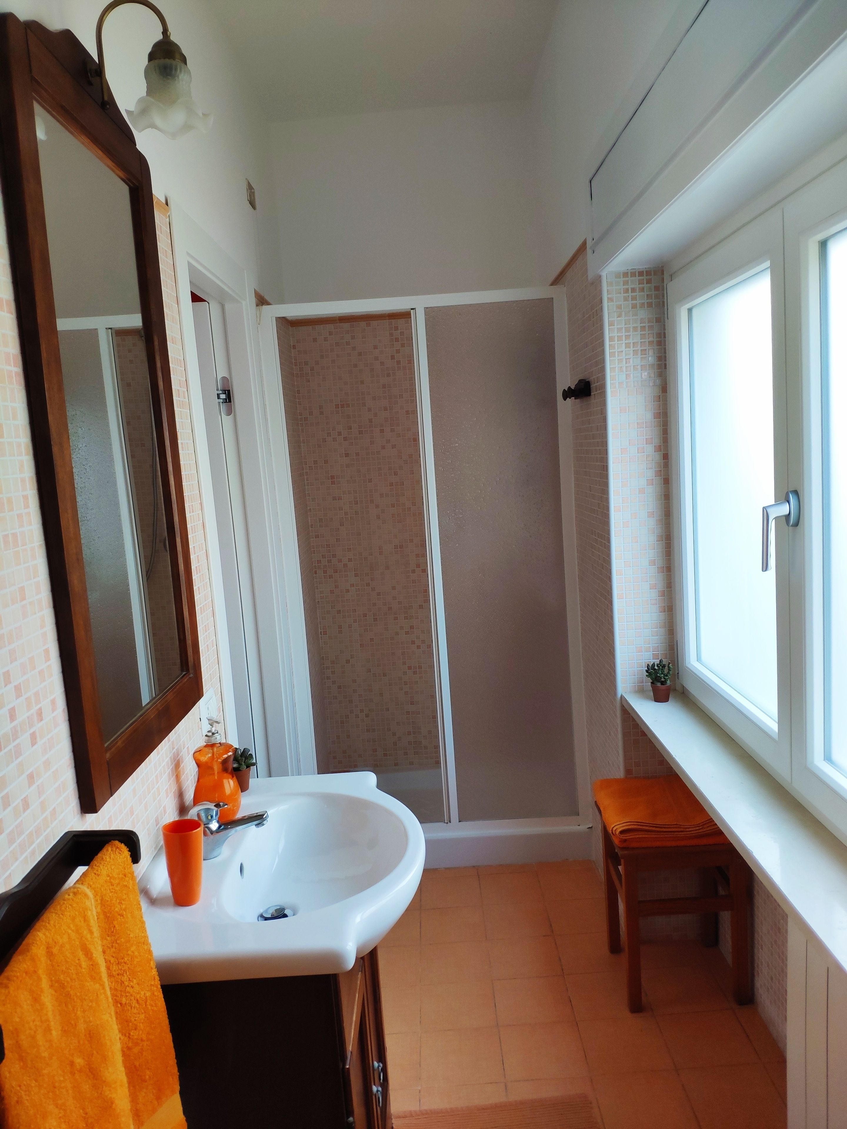 Ein Badezimmer mit Waschbecken, Spiegel, Dusche und Fenster.