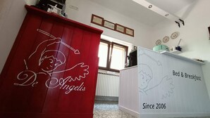 A room with a red cabinet featuring a cartoon angel design and the text "De Angelis". There's a white cabinet labeled "Bed & Breakfast" with "Since 2006". - B&B De Angelis (Ginosa)