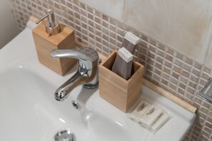 Un lavabo de baño con un grifo moderno, dispensadores de jabón de madera y un jabonera.