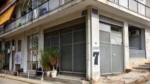 A building with a gated entrance, potted plants, and a sign indicating the number 16. - Smart Location (Athens)