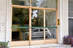 A building entrance with large glass doors, a visible staircase, and a parked car inside. - Smart Location (Athens)