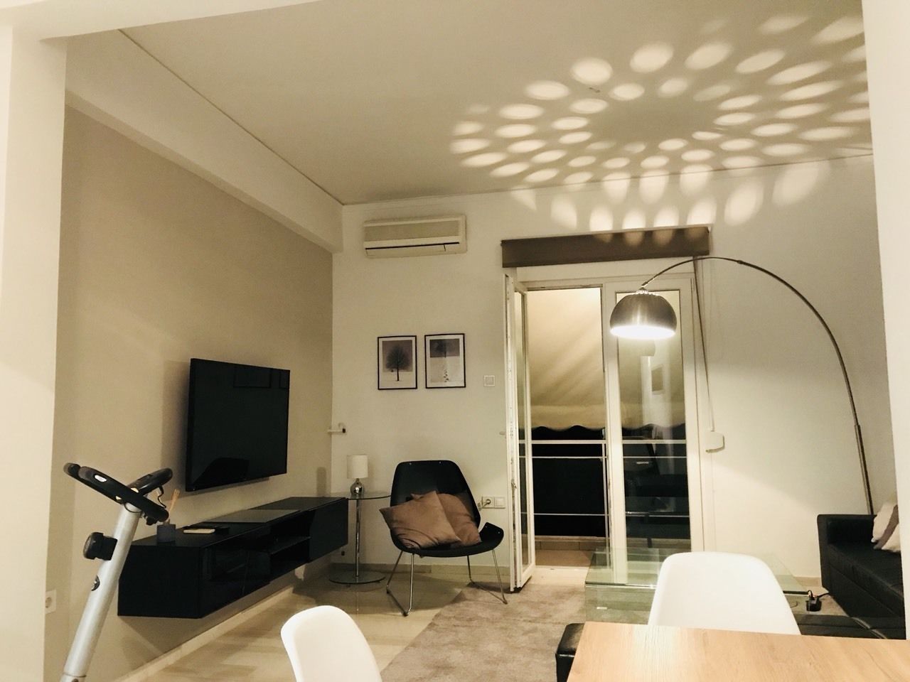 A compact living space with a TV, exercise bike, and a dining area.