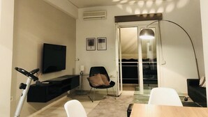A compact living space with a TV, exercise bike, and a dining area. - Renovated minimal aptm next to metro (Athens)