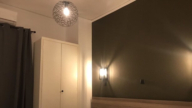 A hotel room with a bed, a wardrobe, a nightstand, and a wall-mounted light fixture. - Renovated minimal aptm next to metro (Athens)