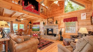 Un intérieur de chalet chaleureux avec une cheminée, des planchers en bois, des canapés en cuir et un coin repas.