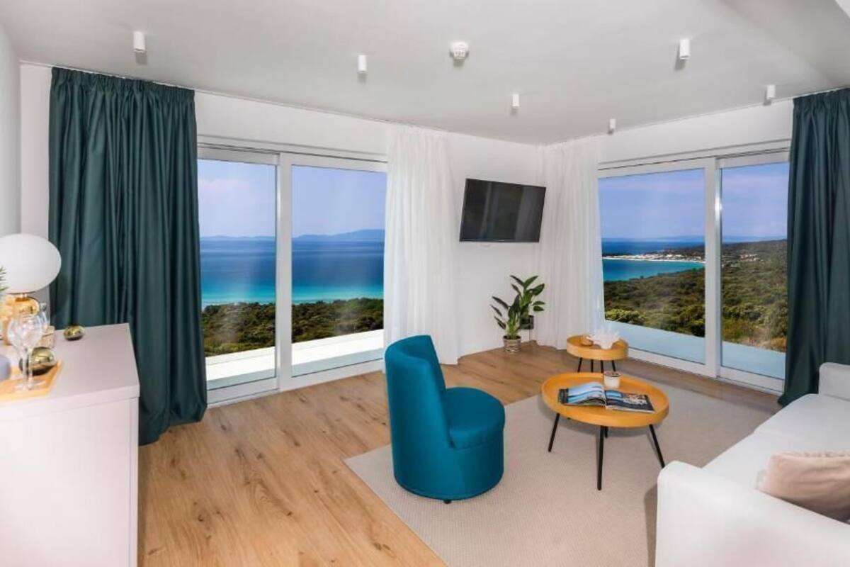 A modern living room with a large window offering a scenic view of the coastline.