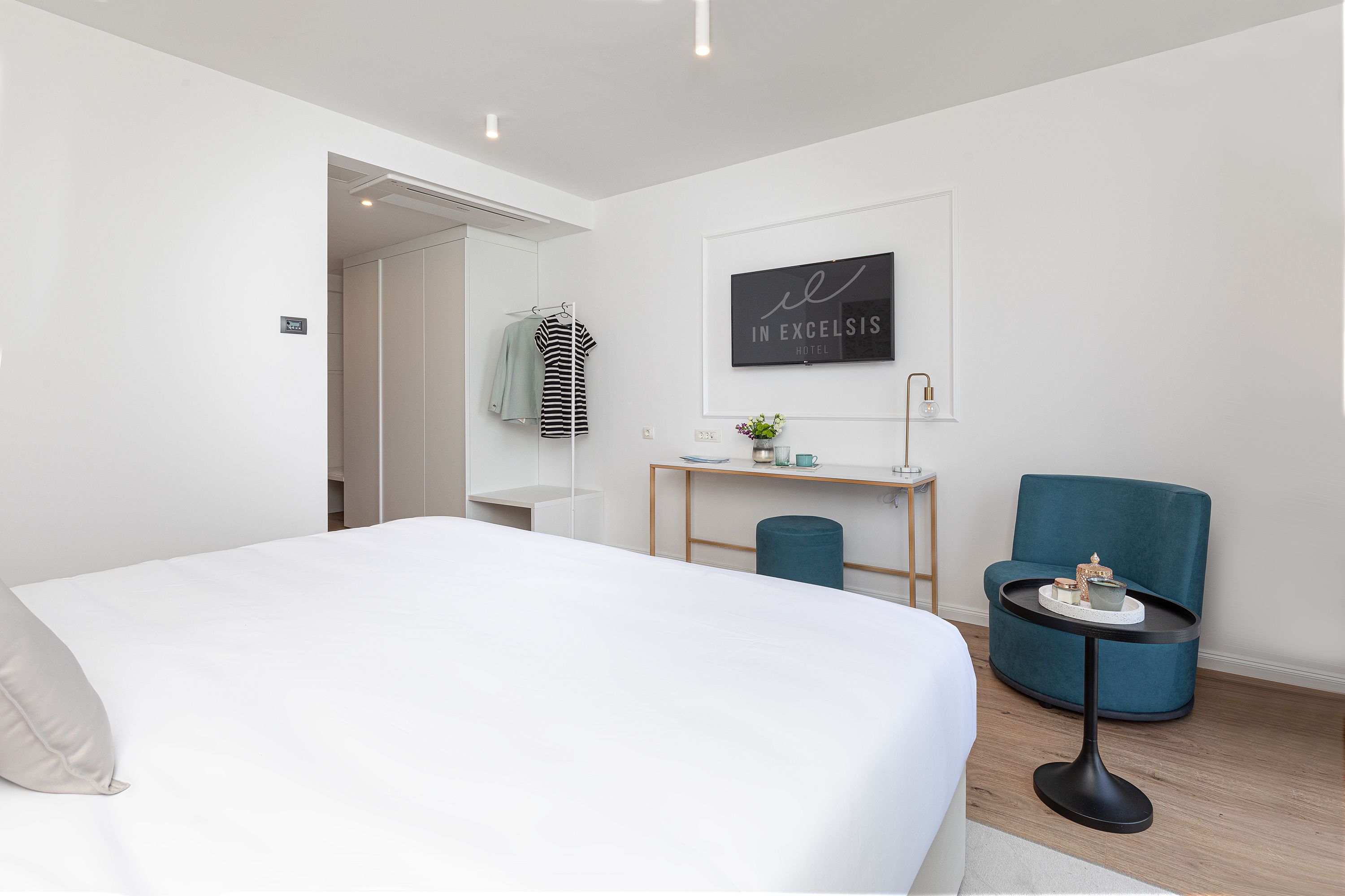 Une chambre d’hôtel moderne avec un grand lit, un bureau avec une chaise et un téléviseur fixé au mur.