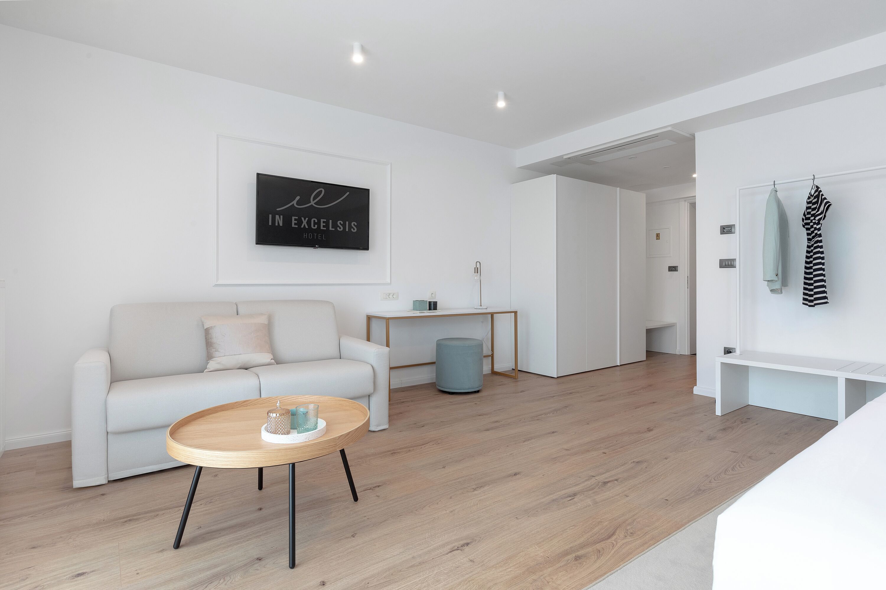 A modern, minimalist living room with a white sofa, a wooden coffee table, and a framed artwork on the wall.