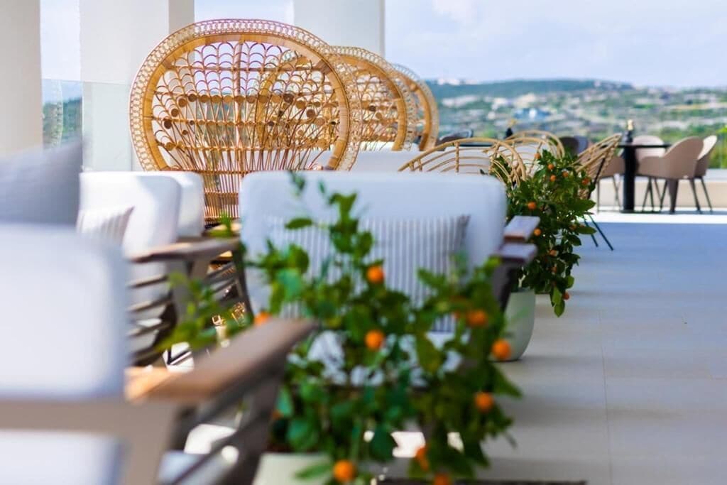 Eine Terrasse mit Korbstühlen und einem Blumentopf mit orangefarbenen Früchten.