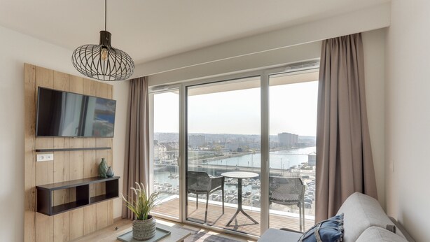 Een moderne woonkamer met een grote televisie, een houten wandmeubel, een eettafel en een bank.