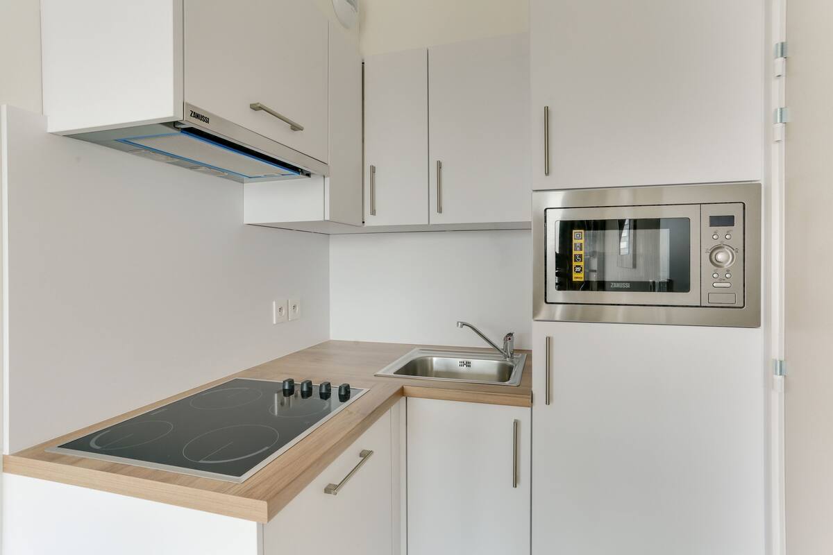 Eine moderne Küche mit weißen Schränken, einem eingebauten Ofen und einer Holz Arbeitsplatte.