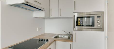 A modern kitchen with white cabinets, a built-in oven, and a wooden countertop.
