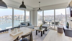 Een moderne woonkamer met een groot raam, een eethoek en een bank.