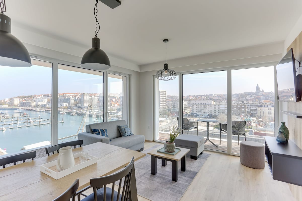 Ein modernes Wohnzimmer mit großem Fenster, Essbereich und einer Couch.