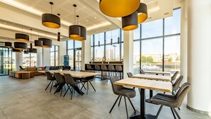 Een moderne eetruimte met hoge plafonds, grote ramen en modern meubilair.