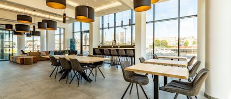 A modern dining area with high ceilings, large windows, and contemporary furniture.