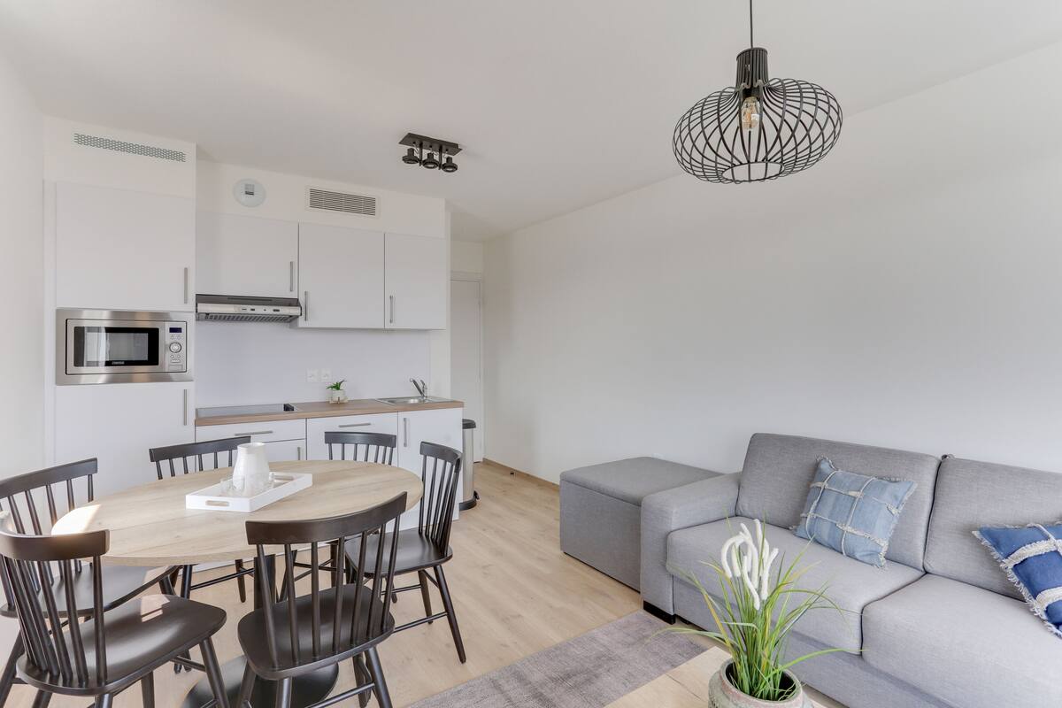 Eine moderne Küche mit weißen Schränken, einer eingebauten Mikrowelle und einem Essbereich mit Holztisch und Stühlen.