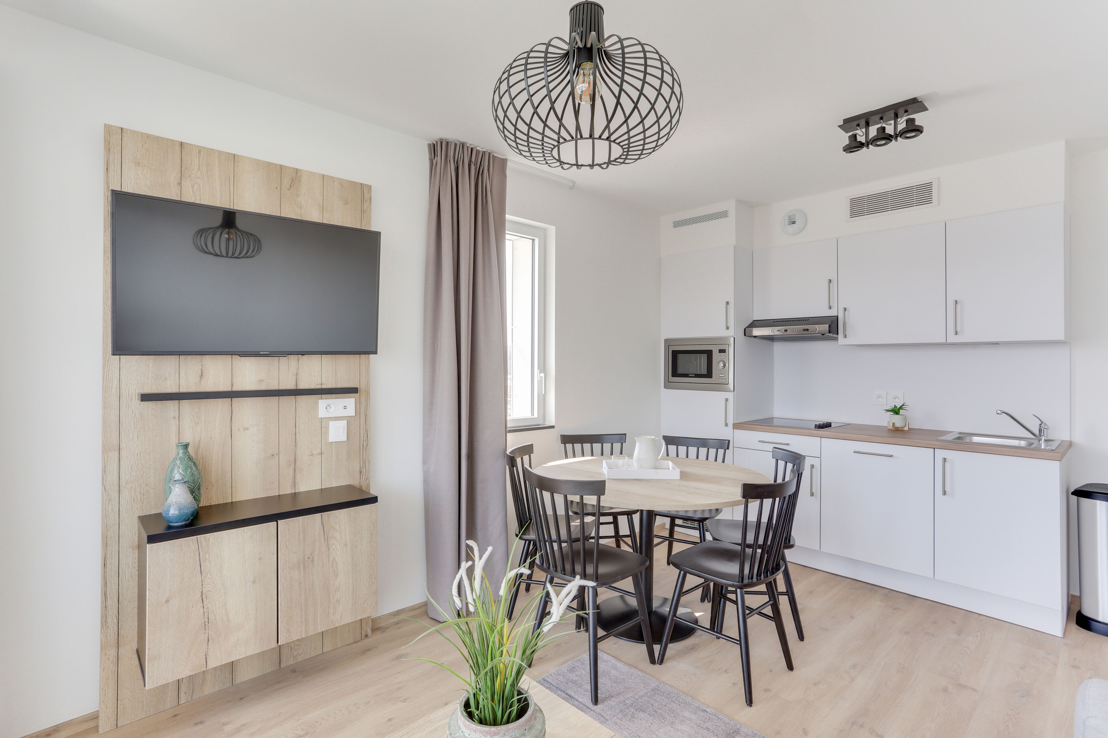 A modern kitchen with white cabinets, a built-in oven, and a stainless steel sink.