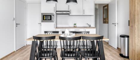 A modern kitchen with white cabinets, a central island, and black pendant lighting.