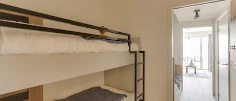 Habitación con literas, una escalera, una mesita y vistas a un balcón.