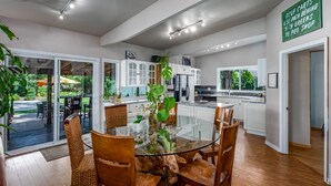 A modern kitchen with white cabinets, a glass dining table, and wooden chairs. - Parkway House - PICKLEBALL COURT- Dog Friendly  - Basketball - FAMILY PERFECT  (Nine Mile Falls)