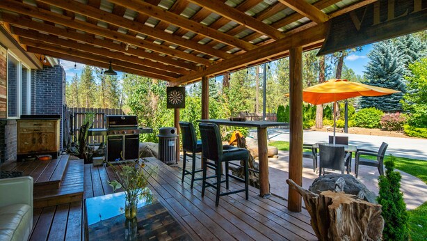 A wooden deck with outdoor furniture, a grill, and a dining table with chairs. - Parkway House - PICKLEBALL COURT- Dog Friendly  - Basketball - FAMILY PERFECT  (Nine Mile Falls)